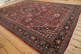 Angled view of a vintage Mahal carpet's intricate floral field and dark navy Samovar-stylized border.