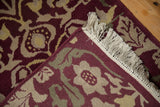 Close-up of Indian Savonnerie rug: burgundy, beige, green blossoms, scrolled vinery, fringe, side cord.