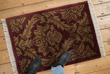 Vintage Indian damask rug mat underfoot, showing scale and its carved burgundy and beige pile.