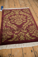 An angled view highlighting the plush, carved pile of the burgundy and dark beige damask rug.