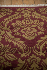 Angled view of the shallow carved contour and plush pile of a vintage Indian damask rug.