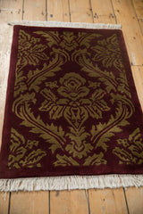 Carved pile and white fringe of a vintage Indian damask rug in burgundy and dark beige.
