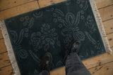 The carved tone-on-tone floral design of a vintage Indian rug shown for scale underfoot.