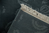 Corner detail showing the rug's hand-knotted foundation, carved pile, and secured fringe.