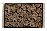 Vintage Indian Arts and Crafts rug with a sprawling leaf pattern in beige and brown on black.