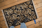 Arts and Crafts style rug with sprawling, carved leaves in neutral tones on a black field.