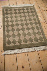 Carved olive green and beige checkered pattern with border on the contemporary Indian rug.