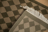 Woven foundation and secure fringe on a hand-knotted Indian checkered rug.