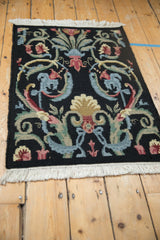 Black Savonnerie rug detail: looped pile, scrolled blue and blush floral blossoms.
