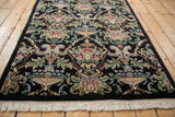 Close-up of Savonnerie rug corner, intricate urn and Rococo leaf motifs, white fringe.