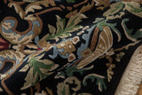 Plush pile of a black Indian Savonnerie rug with Rococo scrolled leaves and fringe.
