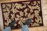 Plush burgundy pile with shallow carved ivory and beige serrated leaves in an Arts and Crafts style.