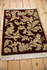 Angled perspective of an Indian Arts and Crafts rug showing its carved beige leaves and white fringe.