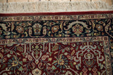 Manufacturer's insignia within the dense navy floral border of a vintage hand-knotted rug.