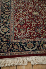 Corner of an Indian Tabriz rug showing the cherry red field, navy border with botehs, and ivory fringe.
