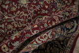 Soft folds of a hand-knotted Indian rug showing the dense wool pile and intricate cherry red design.