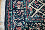 Corner of a vintage Savonnerie carpet showing its floral border, lattice field, and ivory fringe.