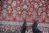 Navy blue floral border in violet and ivory meets cherry red field of vintage Kashan rug.