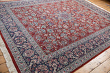 Corner of vintage Pakistani Kashan rug with intricate navy floral border and ivory fringe.