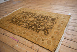 Vintage Indian Oushak rug in gold and olive, angled to showcase its plush, lustrous wool pile.