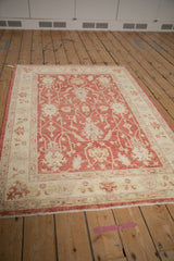 Peshawar rug's ivory floral border, pale cherry red field, and intact side cord.