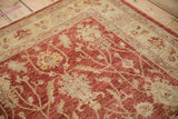 Close-up of vintage Peshawar rug, pale cherry red field with cream floral palmettes.