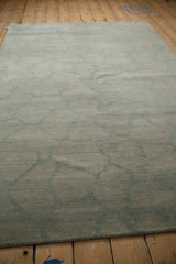 Close-up of the abstract Indian carpet's full pile and dusty celadon green vine pattern.