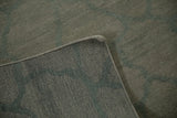 Corner view of the Abstract Indian carpet, showing dusty celadon green pile, woven reverse, and intact selvage.