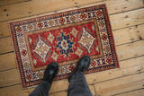 Cherry red abrashed ground of the Pakistani Caucasian rug with sapphire blue diamond motifs.