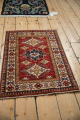 Cherry red abrashed ground of a Pakistani Caucasian rug, with sapphire blue hook and latch motif.