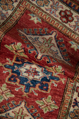 Hand-knotted Pakistani rug with cherry red ground and sapphire blue geometric hook motifs.