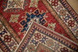 Pakistani Caucasian rug fold, showcasing cherry red, sapphire blue, and beige geometric border.