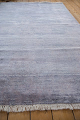 Soft faux silk pile texture in faded blue with horizontal striations and white fringe.