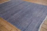 Indian Modern Abstract rug corner with dusty blue abrashes, faux silk texture, and secured white fringe.