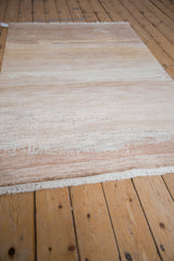 Modern abstract rug with ivory, sand, copper abrashes, varying contour, and fringe.