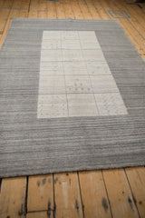Textured silver border of contemporary Gabbeh rug meeting paneled field with simplistic motifs.