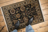 Indian Kashan rug with black field, flowing floral palmettes, meandering vine, and lotus border.