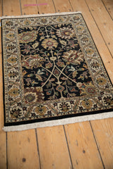 Indian Kashan design rug showcasing black field, colorful palmettes, and ivory lotus border.