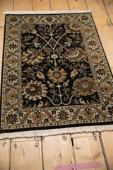Indian Kashan design rug: Ornate floral palmette with serrated leaves on a black field.