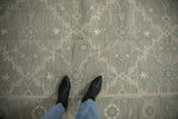 Feet on contemporary Indian Soumac carpet, showing sage green, beige, and silver quatrefoil motifs.