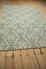 Textured pale jade green and ivory roundel pattern on a Soumac design rug corner.