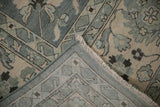 Folded Indian Mahal design carpet revealing slate blue floral pattern, fringe, and tight hand-knotted back.