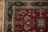 Indian Sarouk rug with burgundy floral field, navy cartouche border, and original fringe.