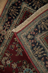 Ivory fringe and burgundy selvage meet a navy, teal, beige floral cartouche border.