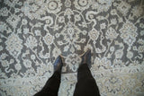 Distressed Agra carpet displaying floral motifs in dark silver and dusty pale ecru.