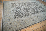 Corner of distressed Agra carpet showing intact side cord selvage and dusty ecru floral border.