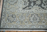 Distressed Agra rug corner showing even pile wear and silver, dusty ecru floral border.
