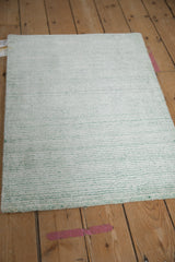 Lustrous abstract rug pile with alternating sea foam green blue and ivory platinum striations.