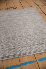 Alternating silver, charcoal striations and intact selvage of an abstract Indian rug.