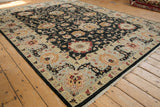Angled view of the Sultanabad carpet's charcoal field and wide border with floral palmettes.